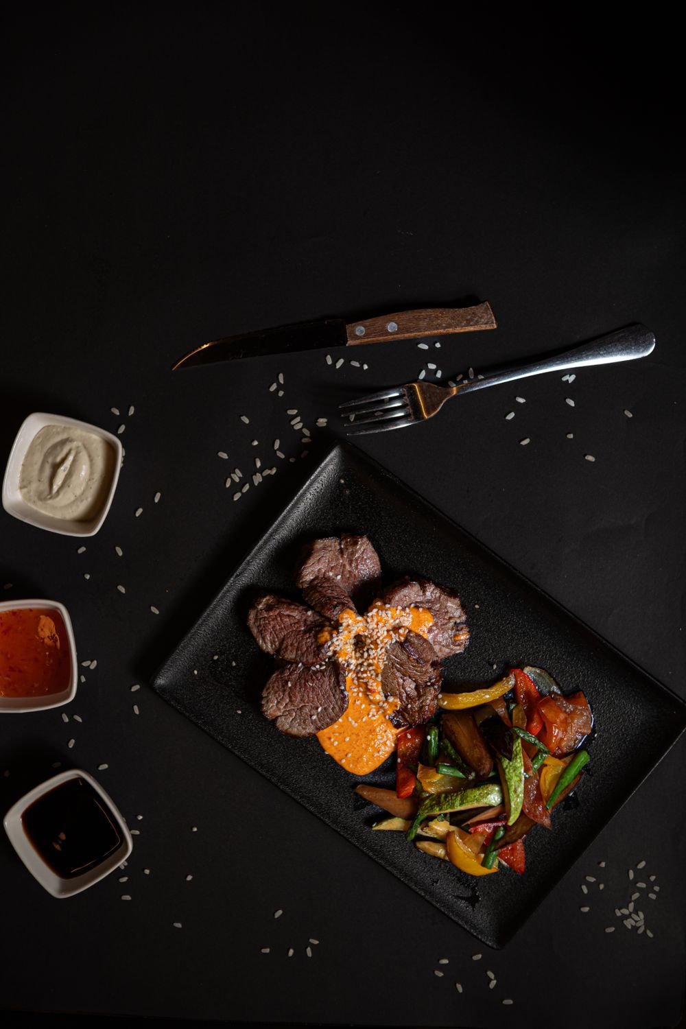 Plato gourmet con carne y vegetales sobre vajilla negra